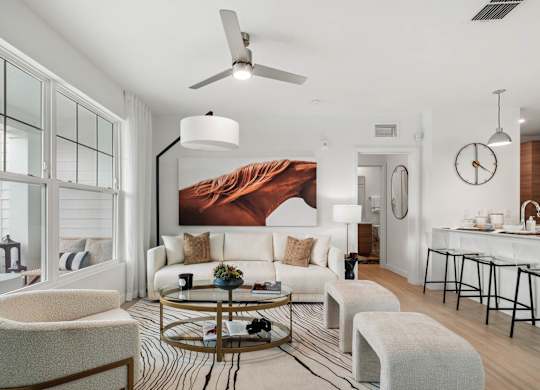 A modern living room with a large painting on the wall and a dining area in the background.