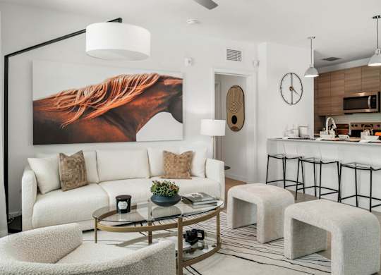 A living room with a white couch, a coffee table, and a large painting of a horse on the wall.