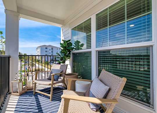 a balcony with two chairs and a table and a window at Altis Twin Lakes Apartments, Florida, 34744