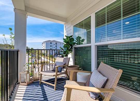 a porch with two chairs and a table and a window at Altis Grand Suncoast Apartments, Florida
