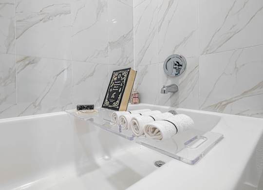 A white bathtub with a book and toiletries on the edge.