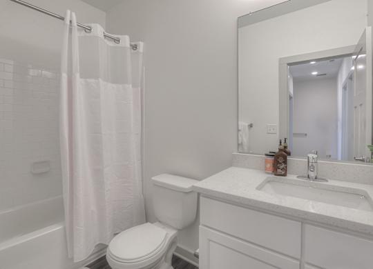 A white bathroom with a toilet, sink, and shower curtain.