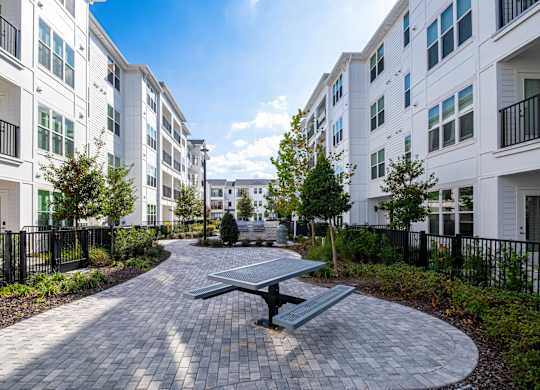 A sunny day at a residential complex with a picnic table in the middle of a paved walkway.