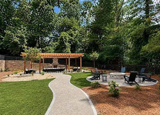 A backyard with a wooden pergola and a concrete patio.