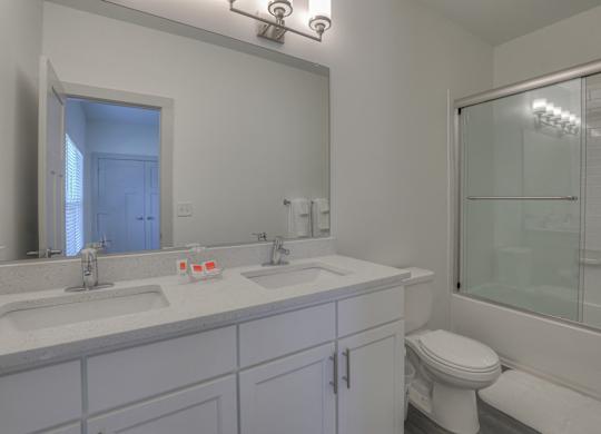 A white bathroom with a toilet, sink, and mirror.