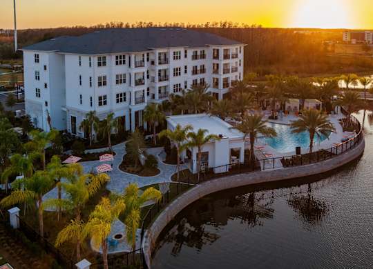 A resort with a pool and palm trees at sunset.