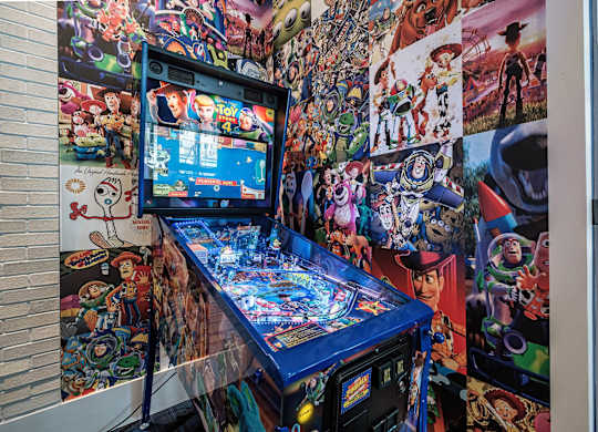 a pinball machine in front of a wall covered in anime pictures at Altis Santa Barbara, Naples, FL