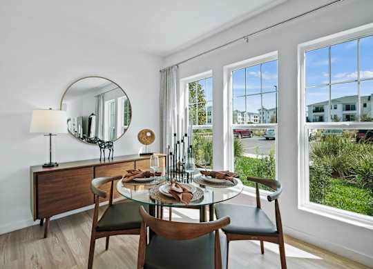 a dining room with a table and chairs and large windows at Altis Twin Lakes Apartments, Kissimmee, FL