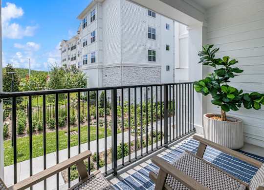A balcony with a bench and a potted plant.