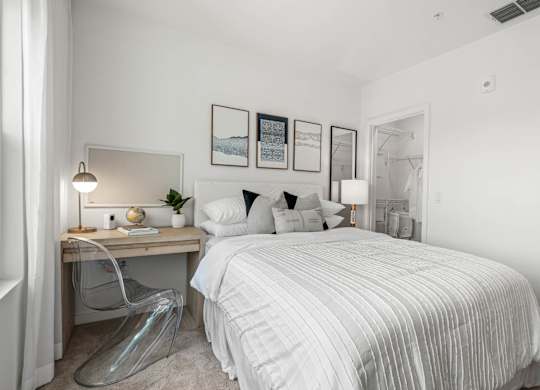 A bedroom with a bed, desk, chair, and pictures on the wall.