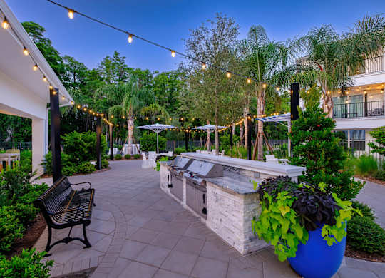 A patio with a bench and a planter is surrounded by trees.
