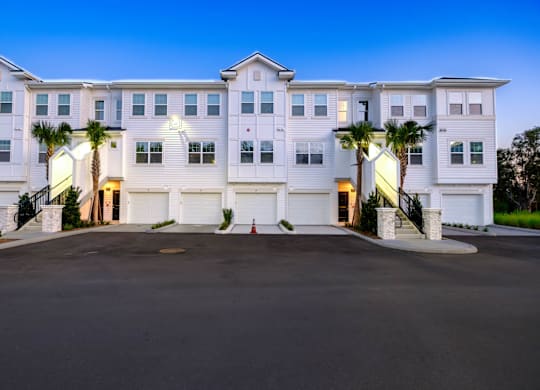 A large white building with a palm tree in front.