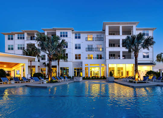 A large white building with a pool in front of it.