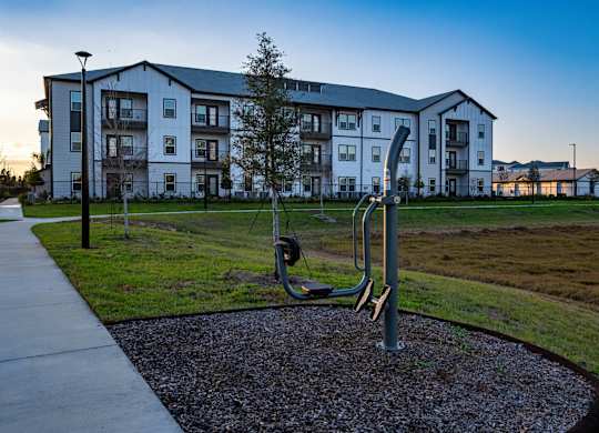 A playground with a slide in front of a large apartment building.at Altis Grand Lake Willis, Orlando