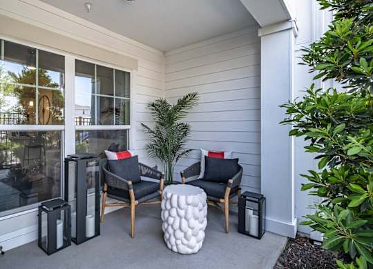 the front porch of a home with two chairs and a table at Altis Grand Lake Willis, Orlando, FL