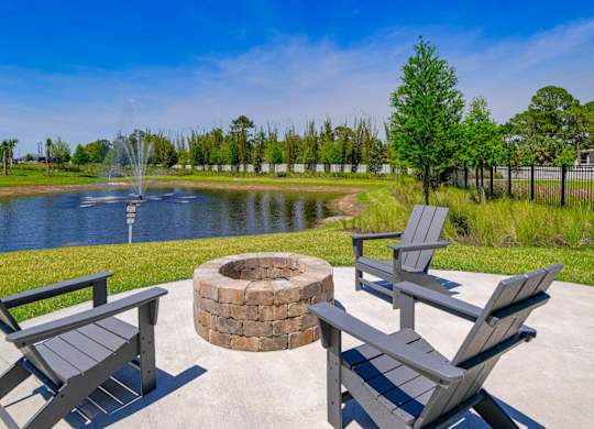 a patio with a fire pit and benches next to a pond at Altis Grand Lake Willis, Orlando, FL 32821