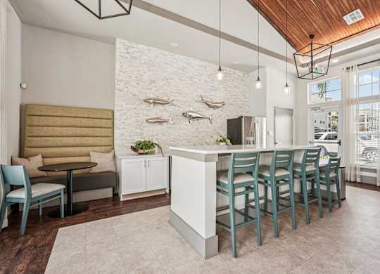 A modern kitchen with a white island and teal chairs.
