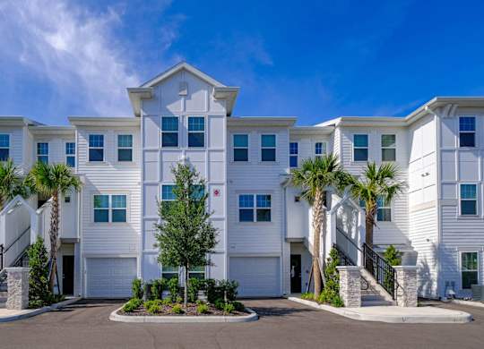a building with palm trees in front of it at Altis Grand Lake Willis, Florida, 32821