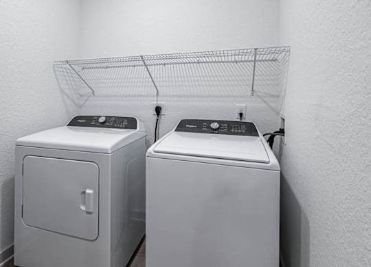 two washers and dryers in a laundry room with a rack on the wall at Altis Grand Lake Willis, Orlando, 32821