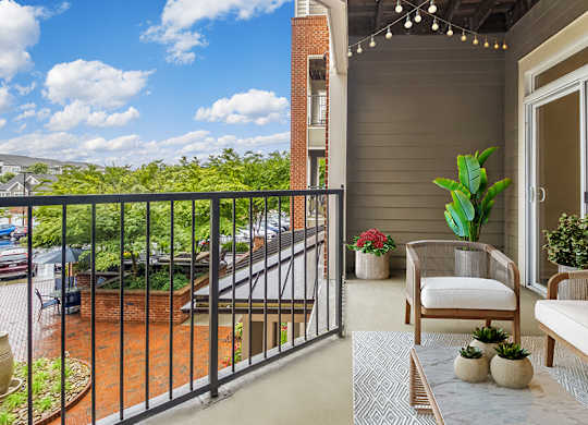 A balcony with a white couch, a chair, and a potted plant.