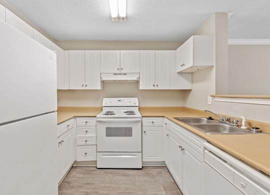 A white kitchen with a refrigerator, oven, and sink.