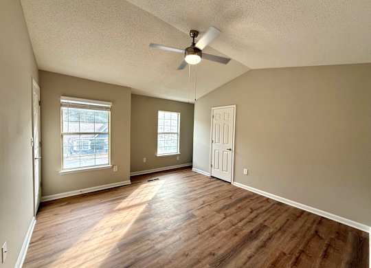 A room with a ceiling fan and wooden flooring.