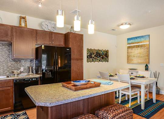 A kitchen with a refrigerator, sink, and dining table.