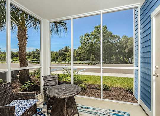 A patio with a table and chairs overlooking a pool.