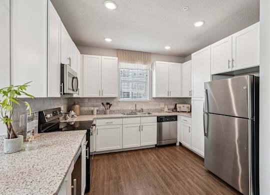 A kitchen with white cabinets and a stainless steel refrigerator.