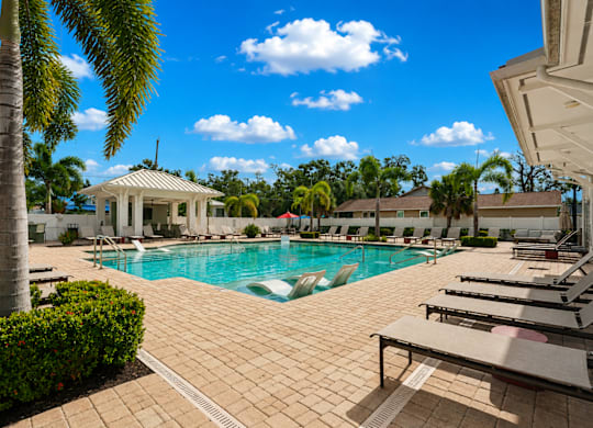 A pool surrounded by a patio and a gazebo.