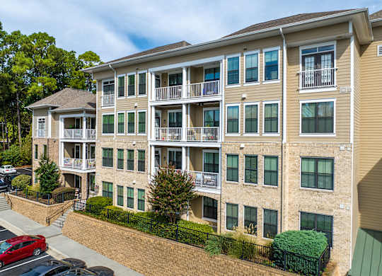 A multi-story apartment building with a red car parked in front.