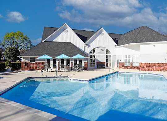 Charlotte, NC, Apartments Near ALDI - Coffey Creek - A Bright Outdoor Swimming Pool With Brick Accents, Patio Seating, Blue Umbrellas.