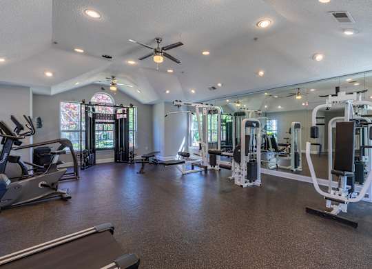 A spacious gym with a variety of equipment and a large mirror on the wall.