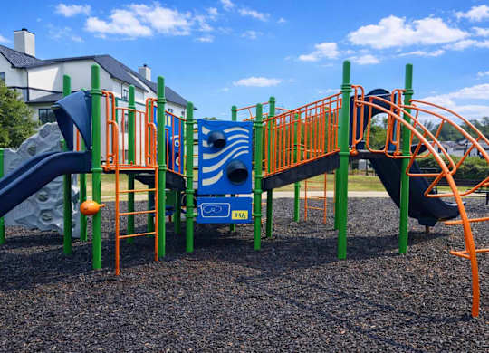 A playground with a blue slide and orange railings.