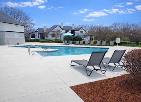 A pool with a few chairs around it.