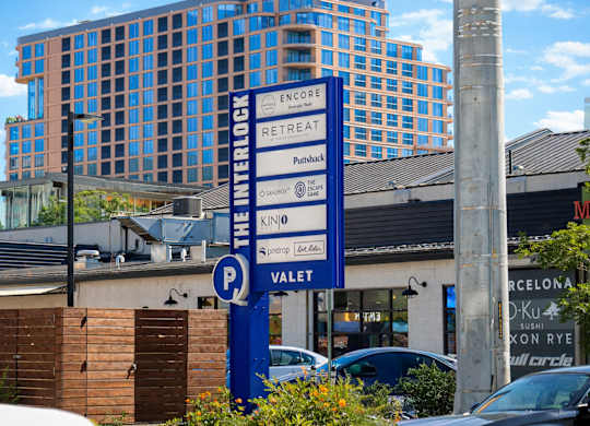 A blue sign with white text on it in front of a building.