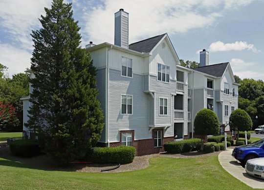 A large two-story apartment building with a parking lot in front.