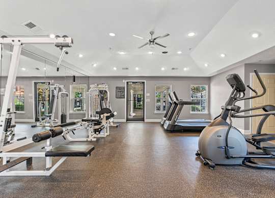 A spacious gym with a variety of equipment including treadmills, weights, and a stationary bike.