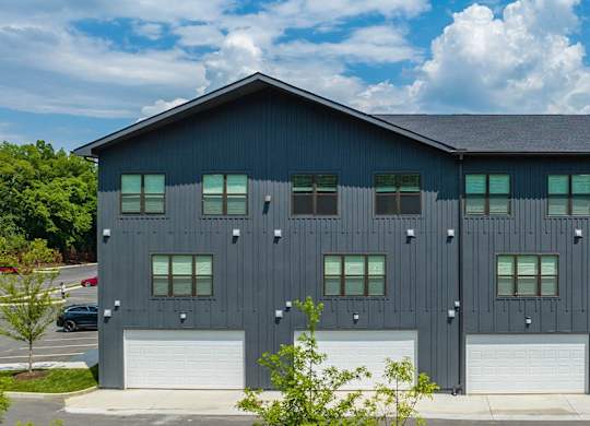 the front of a black building with white garage doors