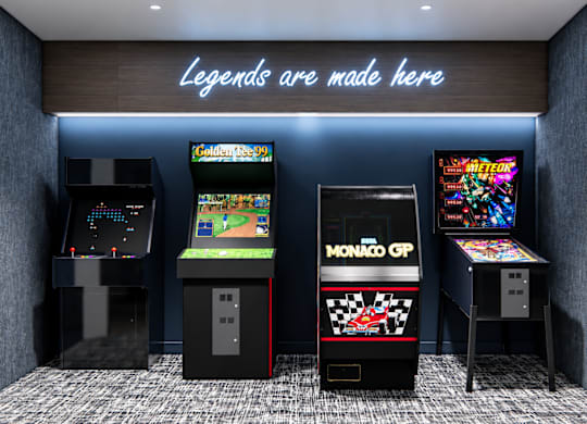 A row of arcade games including Monaco GP and Golden Tee 99.
