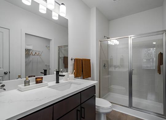 A modern bathroom with a white countertop and a walk-in shower.