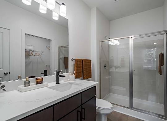 A modern bathroom with a white countertop and a walk-in shower.