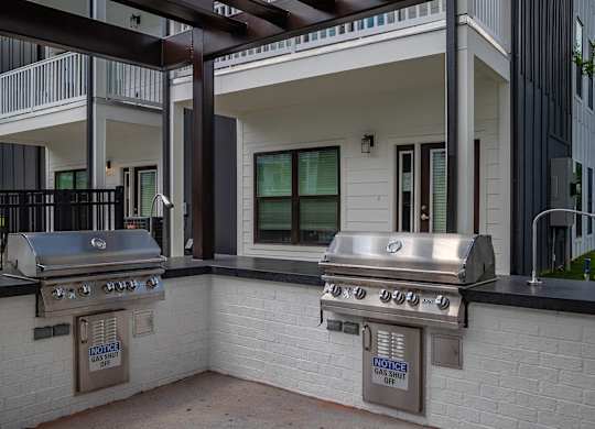 two stainless steel barbecue grills in front of a building