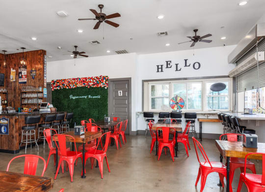 a restaurant with red chairs and tables and a bar