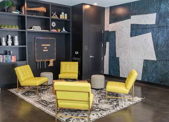 A living room with a black bookshelf and yellow chairs.