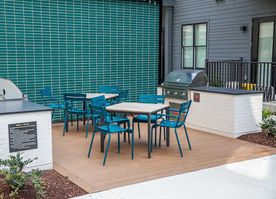 A patio with a table and chairs and a grill.