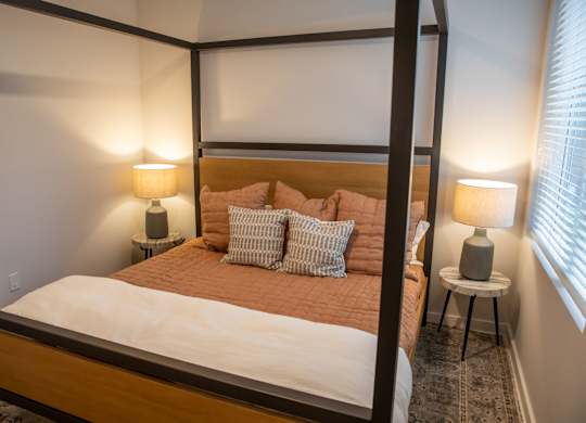 A bed with a brown headboard and white bedding is in a room with two lamps on side tables.