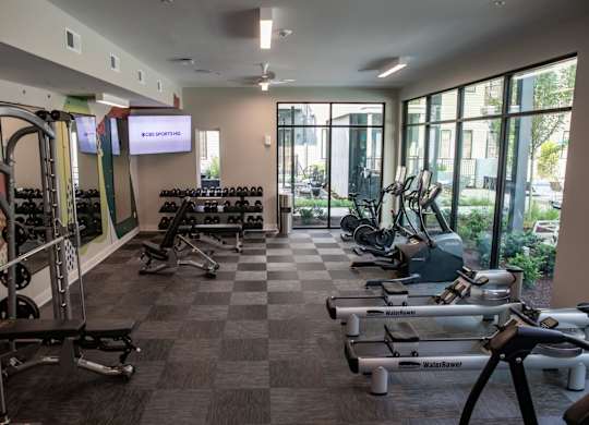 A gym with a variety of equipment including treadmills, weights, and exercise machines.