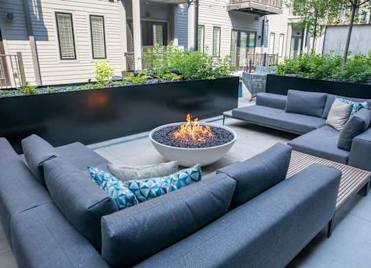 A modern outdoor seating area with a fire pit in the center.