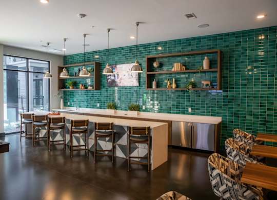 A modern kitchen with a green tiled backsplash and wooden furniture.
